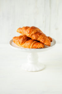 Weißer Tortenständer mit frischen Croissants Weißer Tortenständer mit frischen Croissants